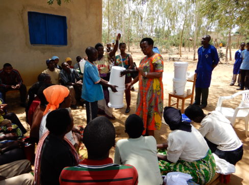 Woman demonstrating to a group of adults how to use and maintain the SAM3 household filter.